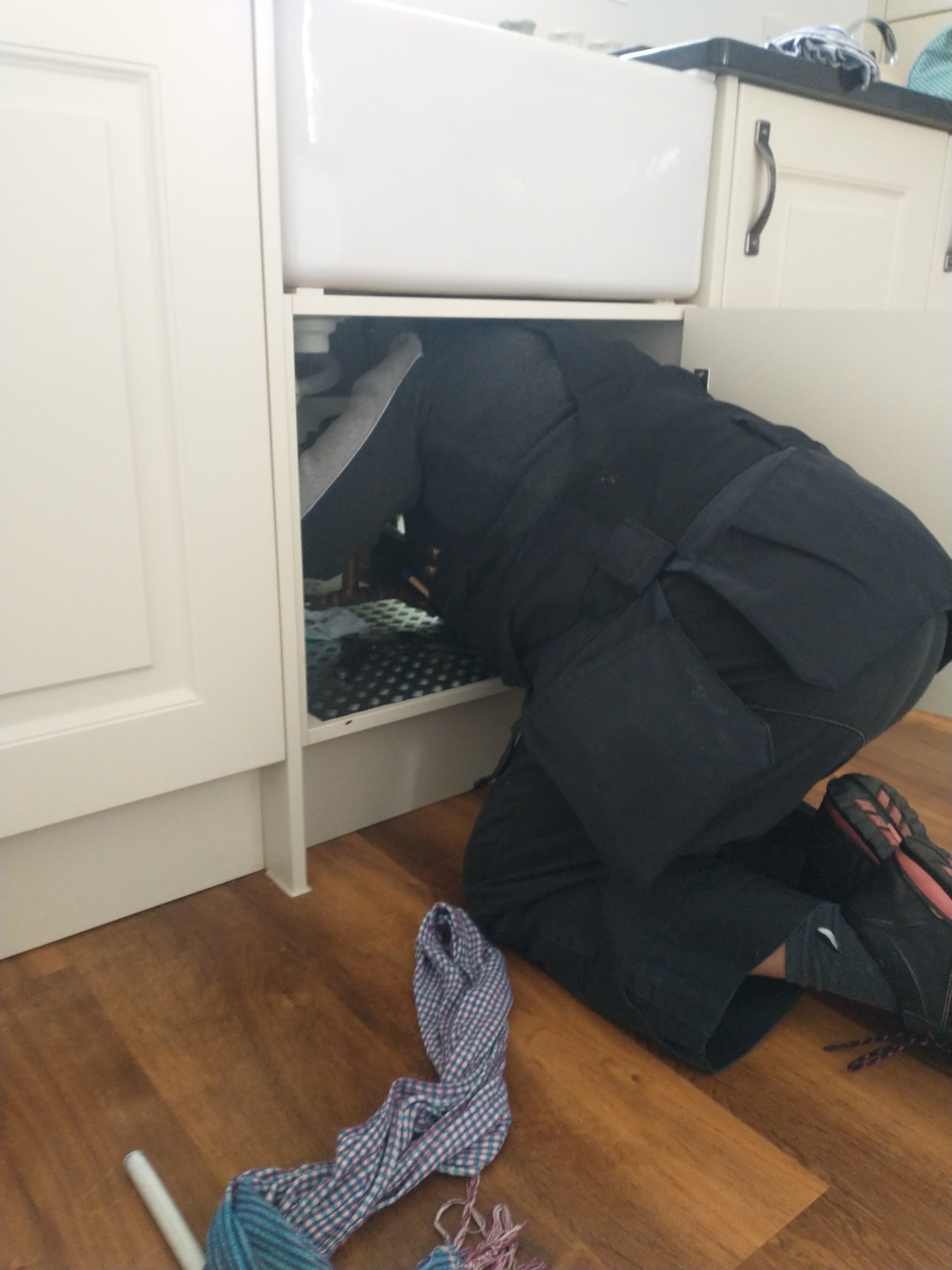 Working under a Belfast sink unit in a kitchen