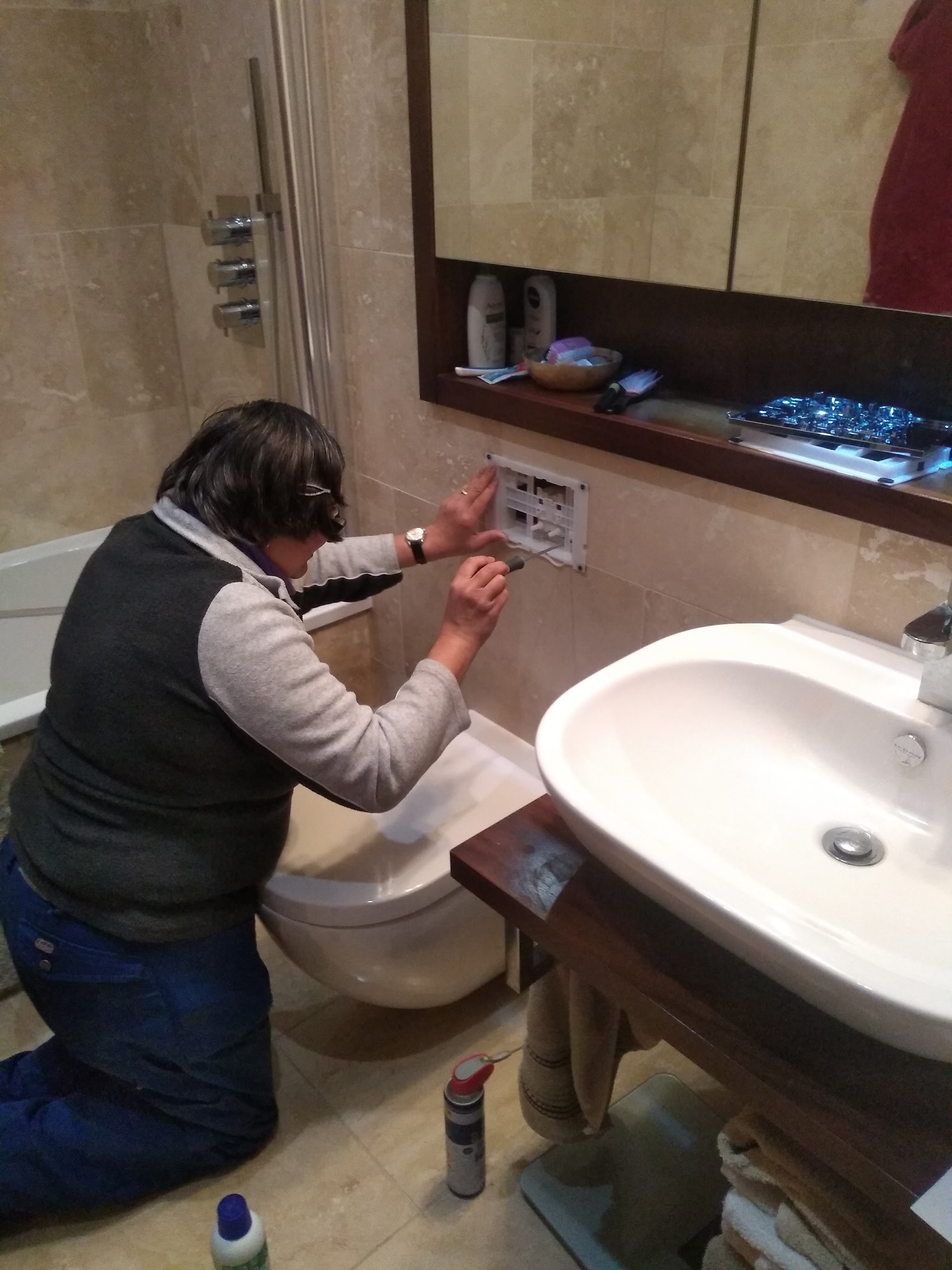Working on a bathroom wall panel beside the basin