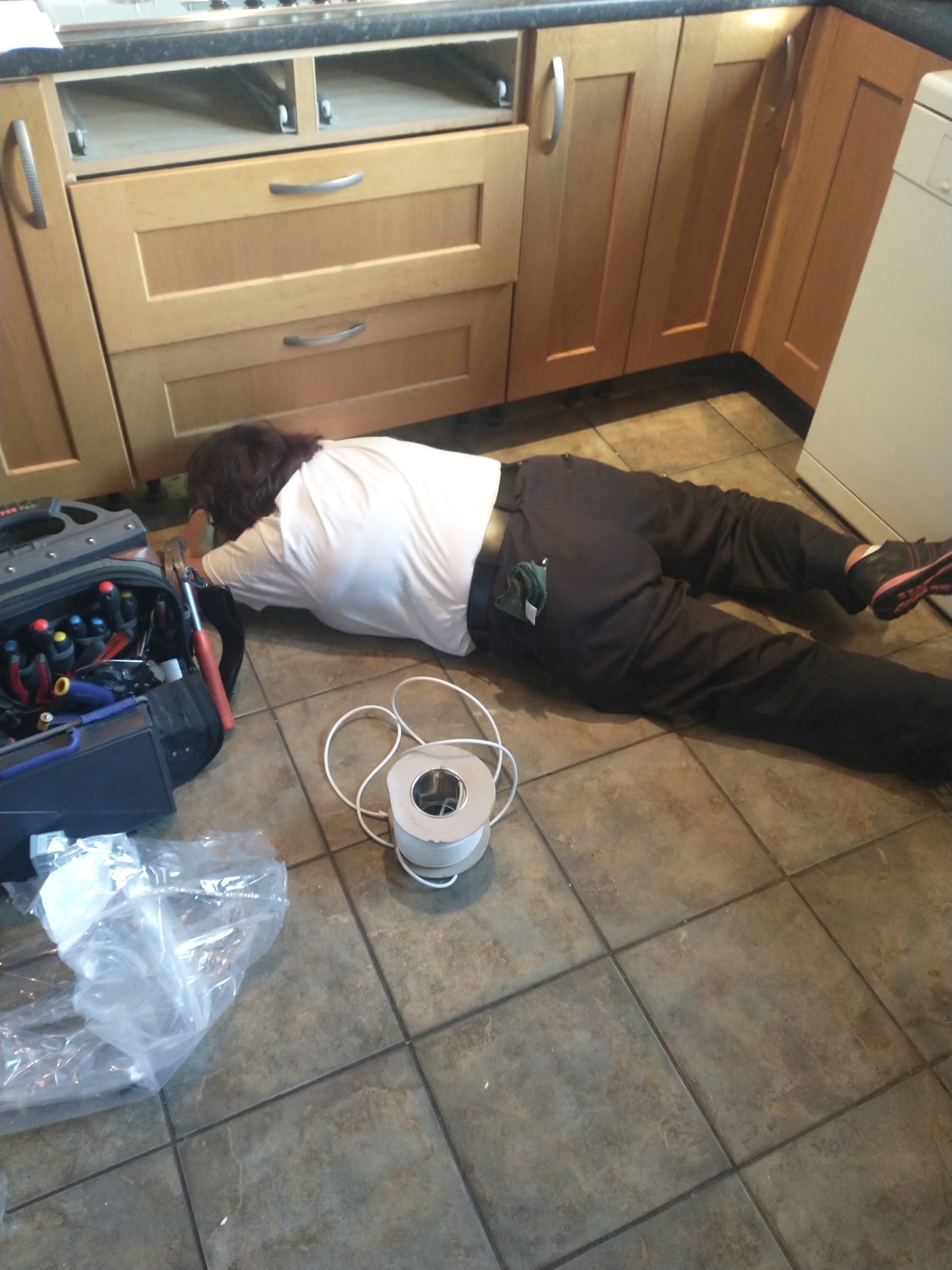 Flat on the kitchen floor, working under the units