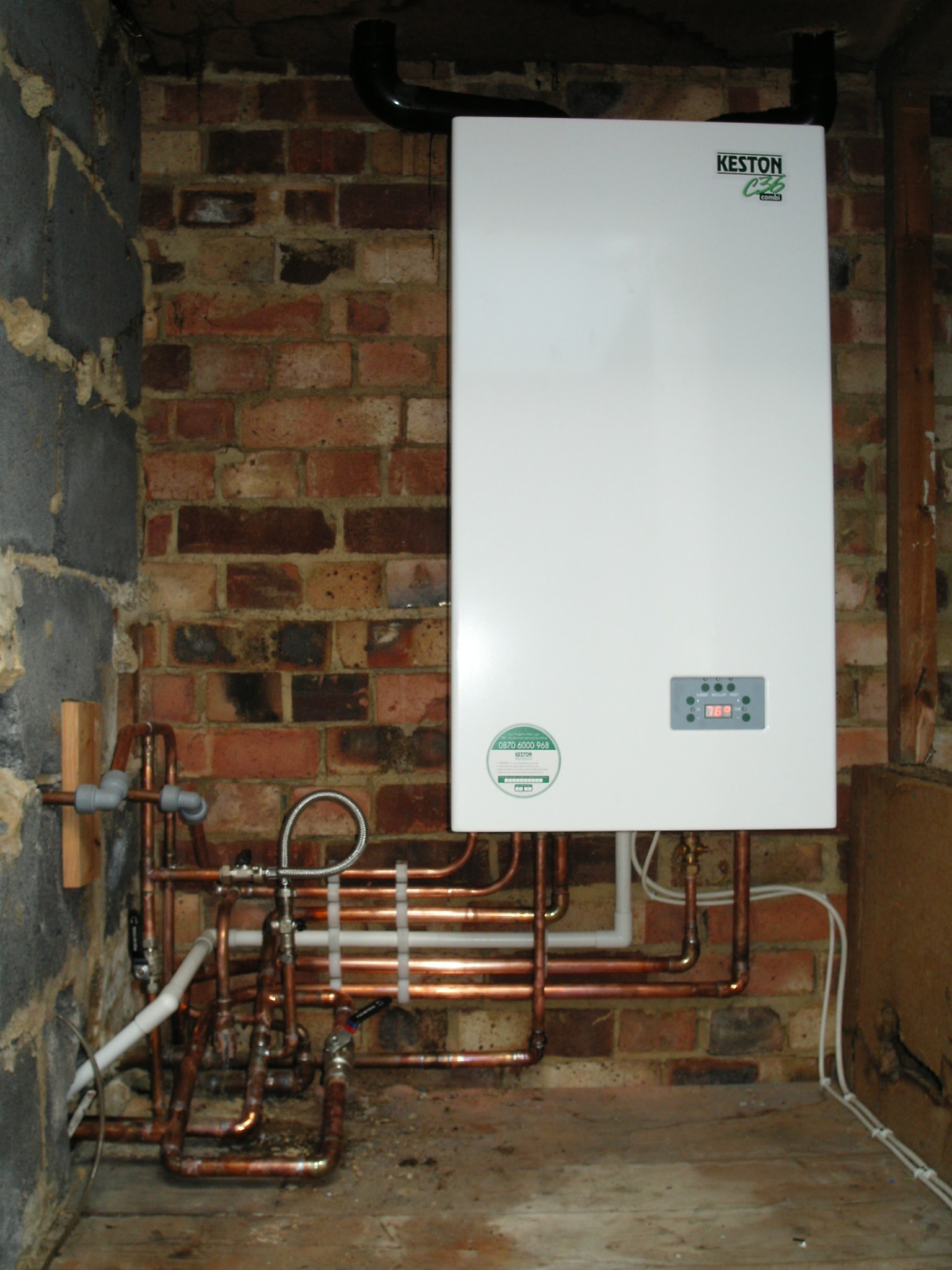 A newly fitted wall boiler with copper pipework against a brick wall