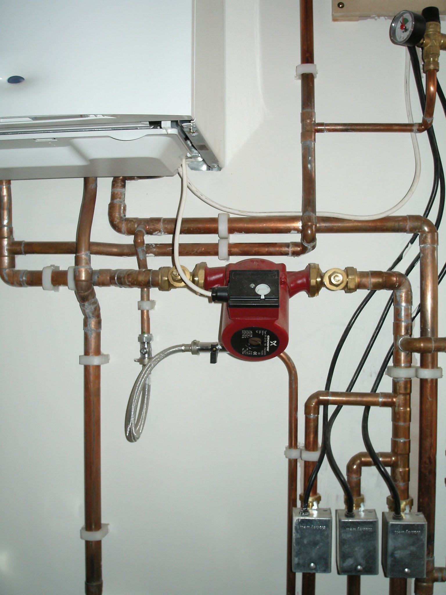 Copper pipework, pump and zone valves below a boiler